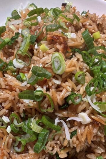 White bowl with rice pilaf garnished with scallions