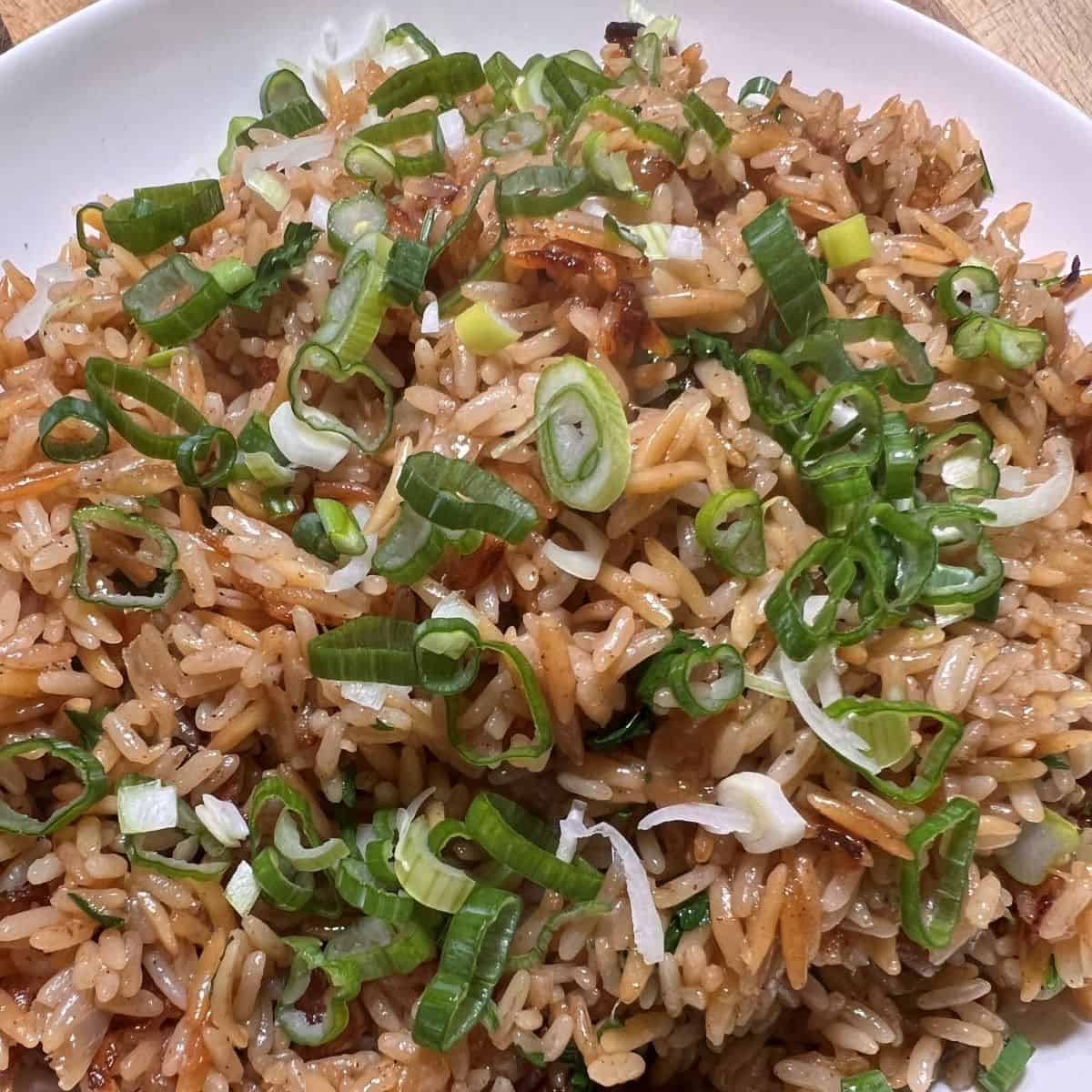 White bowl with rice pilaf garnished with scallions