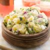City Bargeque potato salad on a wooden bowl with a pink drink in the background