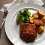 chicken thigh with broccoli and roasted potatoes on a white plate