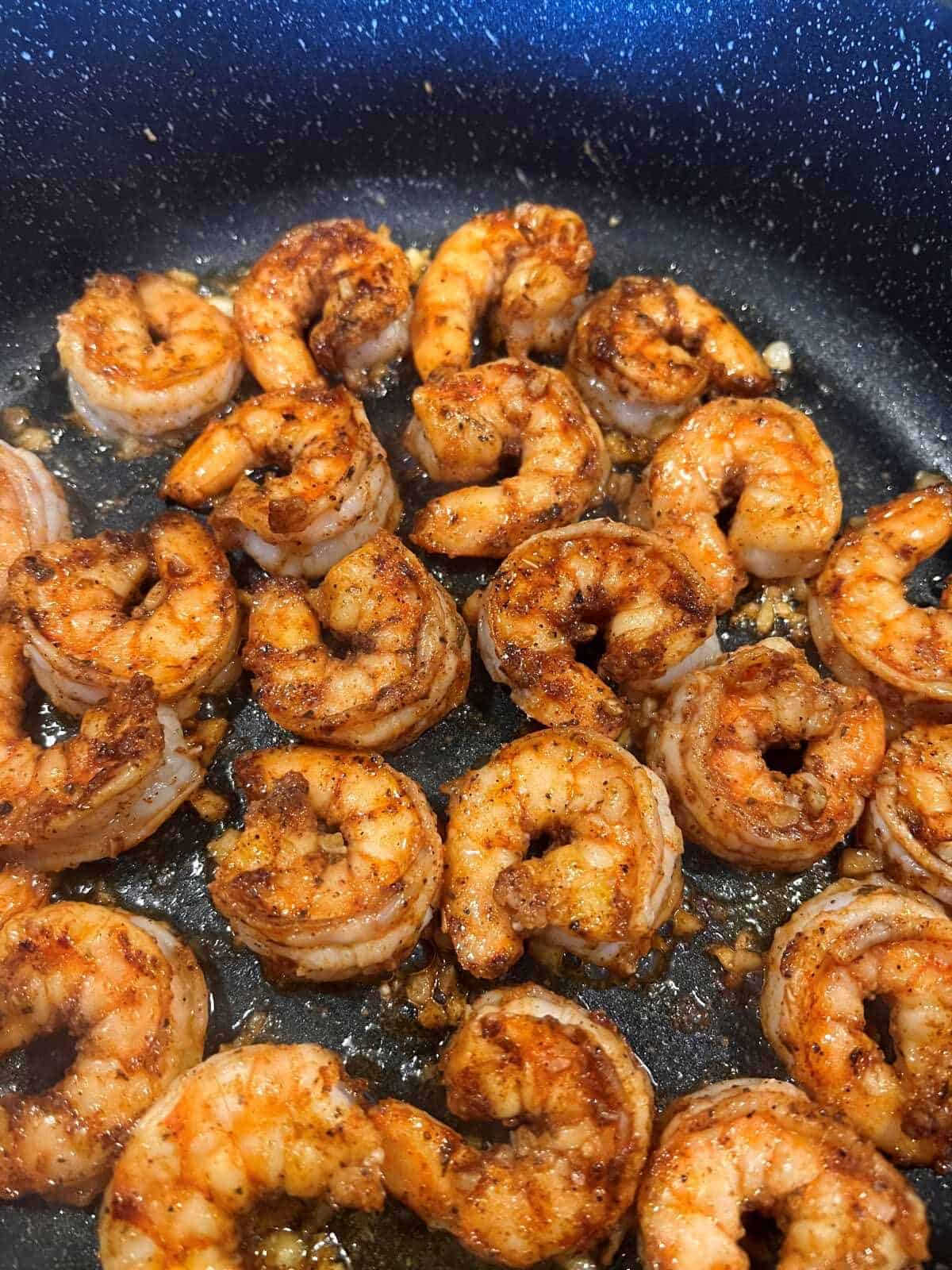 Shrimp that have been cooked on one side in a skillet
