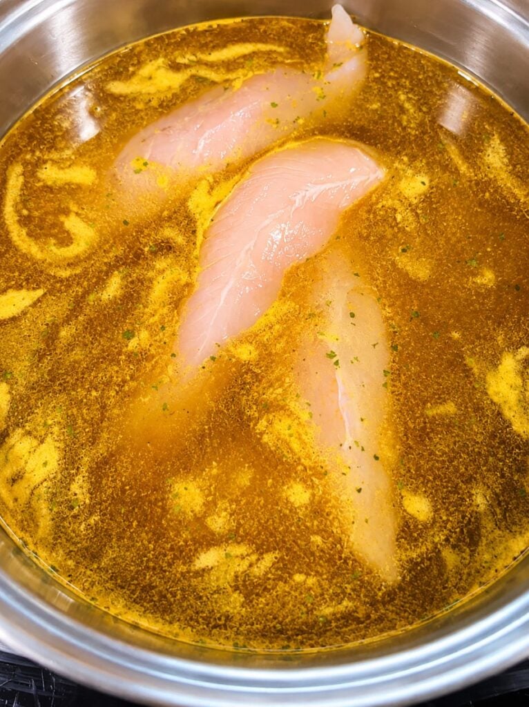 Chicken tenders poaching in chicken broth