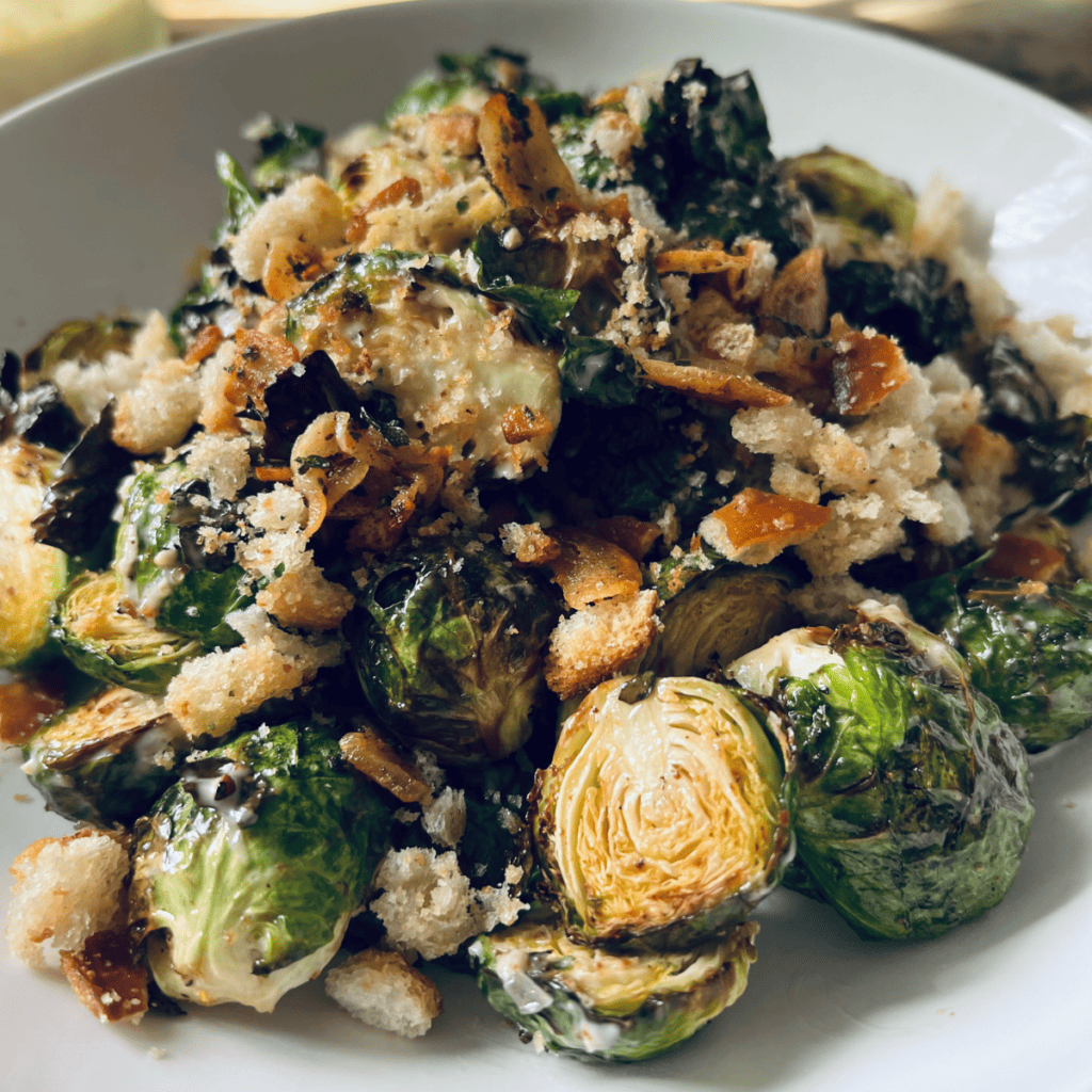 Roasted Brussels sprouts in a white bowl with homemade garlic butter bread crumbs