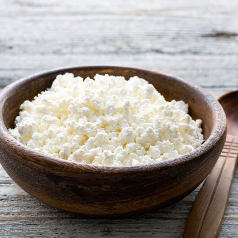 Homemade ricotta cheese in a brown wooden bowl