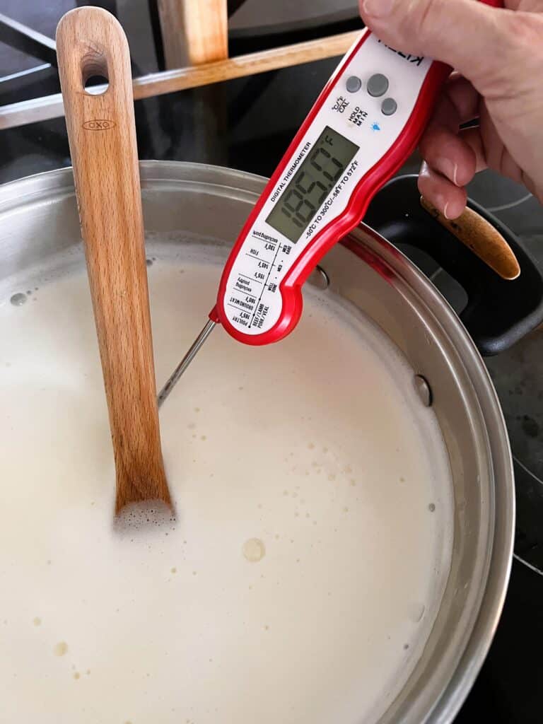 Pot with hot milk and a thermometer reading 185 degrees F