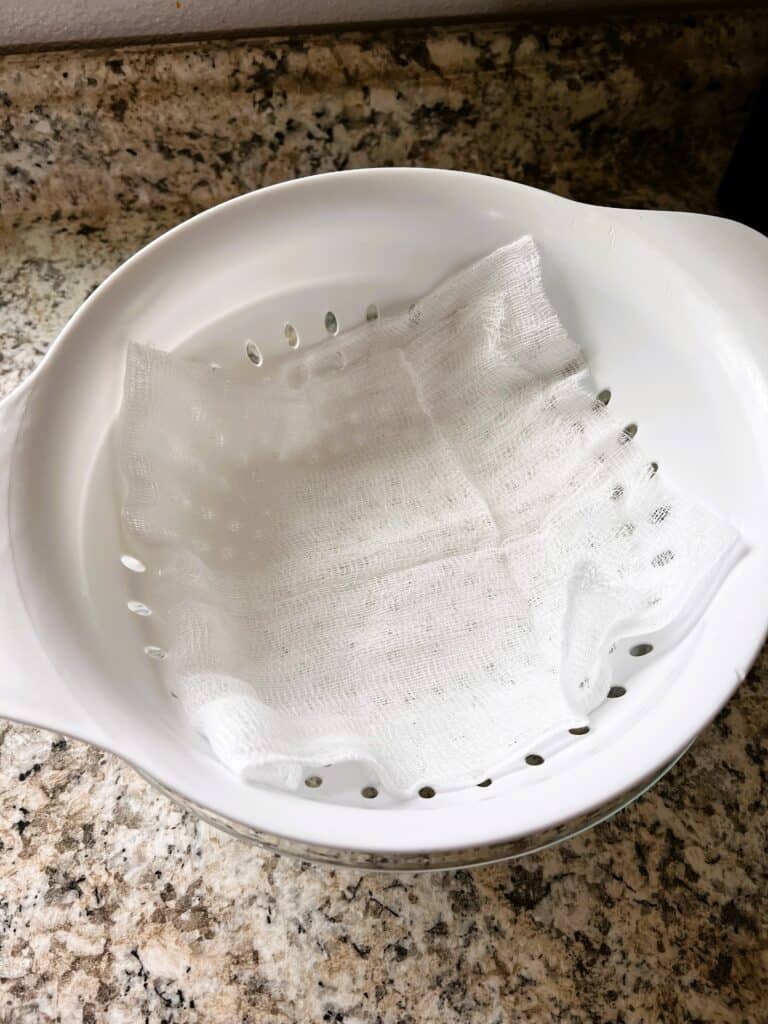 Colander lined with cheesecloth over a large bowl