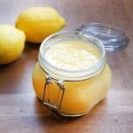 Finished Lemon Curd in a jar on a table with 2 lemons