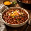 Bowl of Texas style chili with cheese and onions on top