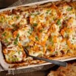 Baking dish with baked ravioli lasagna and a spoon
