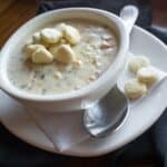White bowl with New England Clam Chowder and oyster crackers. Sppon and napkin.