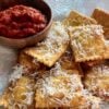 Toasted Ravioli on a white plate with marinara sauce