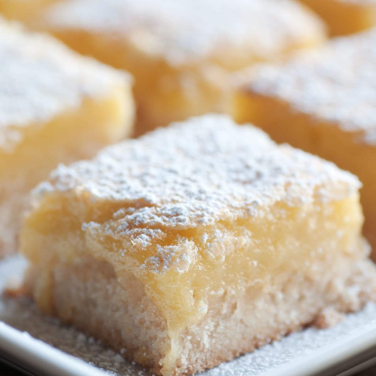 Lemon Gooey Butter Cake cut into bars and sprinkled with powdered sugar.