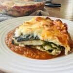A slice of the finished chile relleno casserole on top of ranchero sauce on a white plate