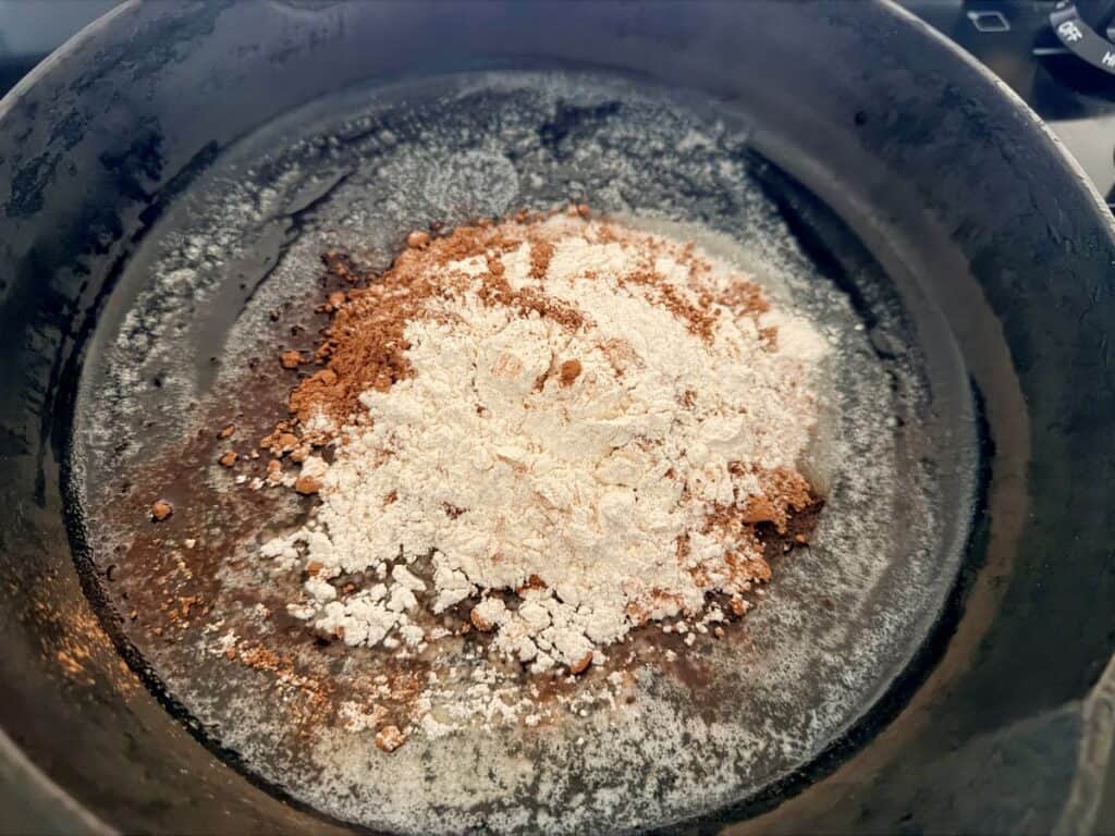 Flour and cocoa added to melted butter in skillet – Dry ingredients piled on top of the butter.