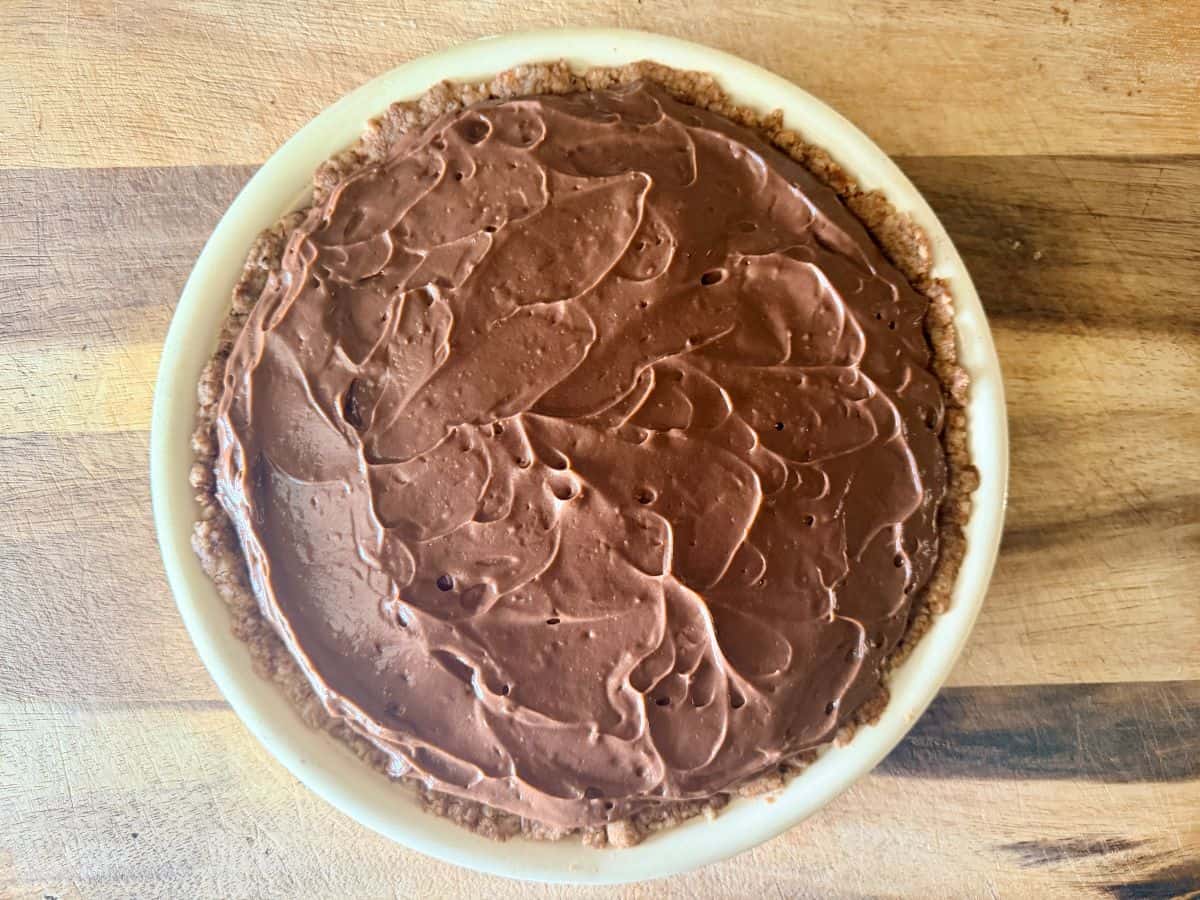 Chocolate pudding layer spread over the cream cheese layer, covering the entire pie.