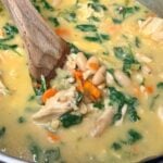 Close-up of creamy chicken and white bean soup with spinach, carrots, white beans, and chopped chicken.