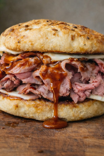 Messy homemade North Shore 3-way roast beef sandwich on an onion roll with barbecue sauce and melted cheese.