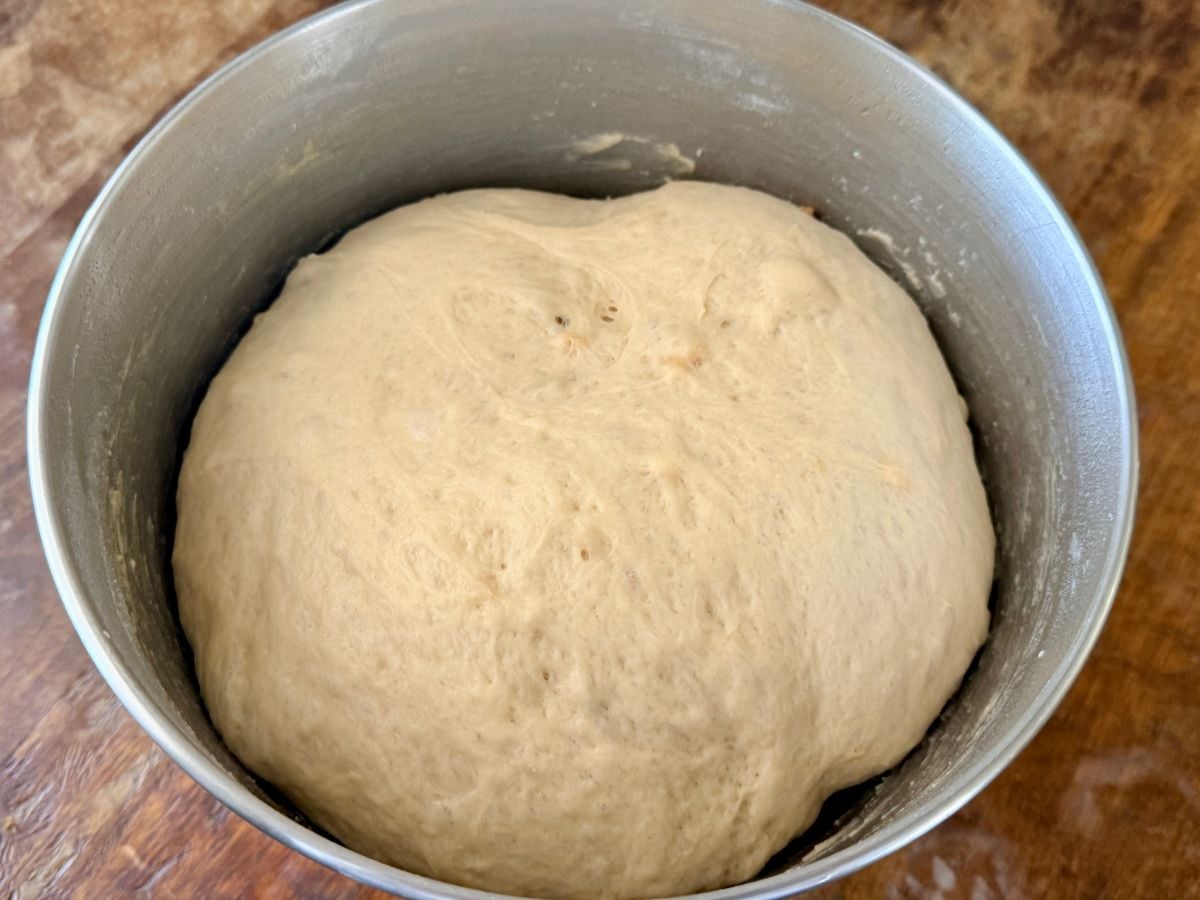 Onion roll dough doubled in size during the first rise in a mixing bowl.