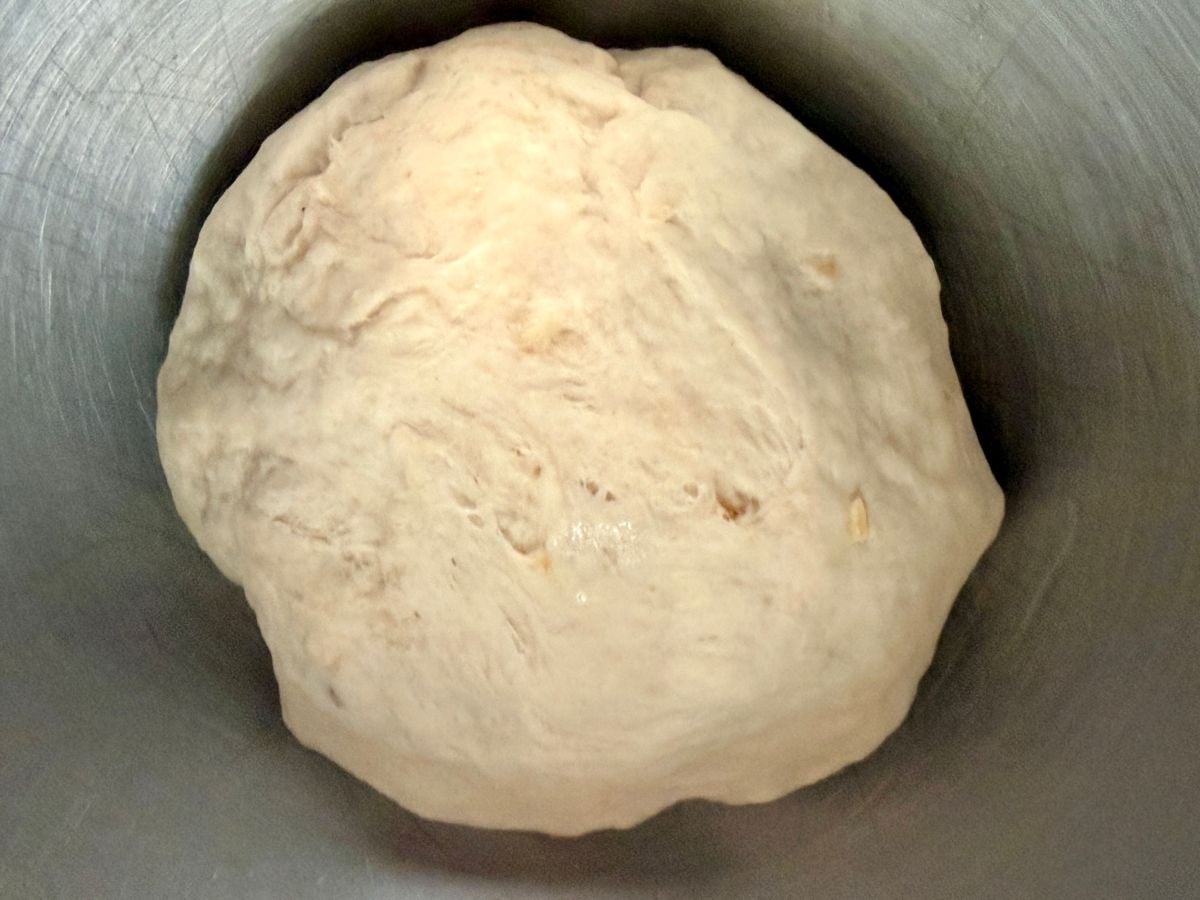 Smooth kneaded dough for homemade onion rolls resting in a mixing bowl.