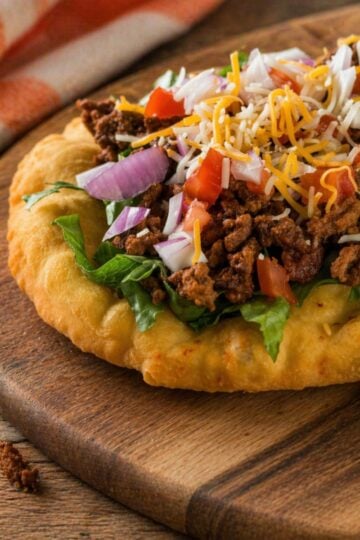 Indian fry bread taco topped with ground beef, lettuce, tomatoes, and shredded cheese
