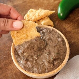 restaurant-style black bean dip with tortilla chip being dipped