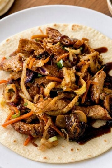 Homemade moo shu pork served in a warm flour tortilla with extra hoisin sauce.